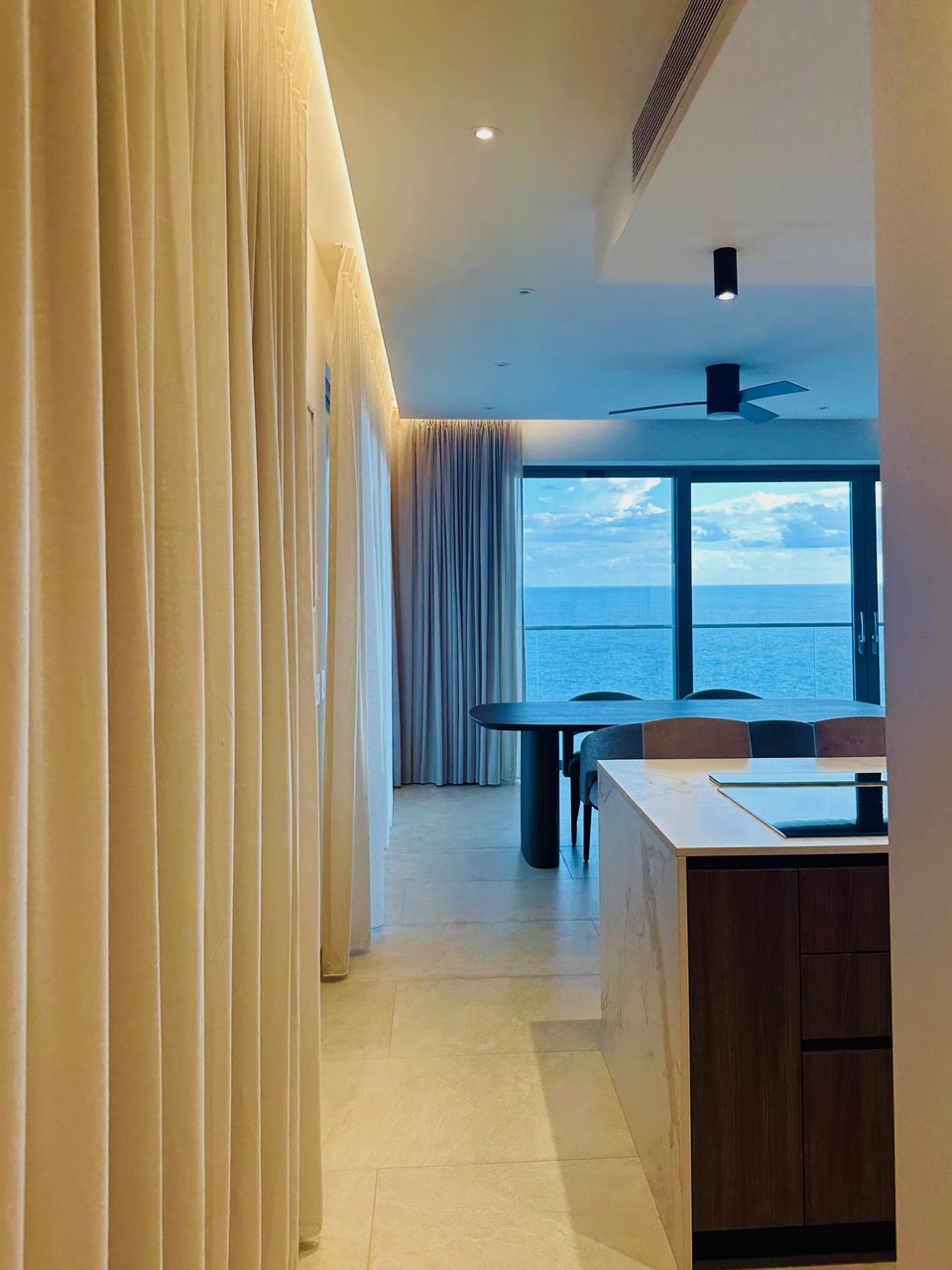 Ocean-view kitchen and dining area at Panorama Residences in the evening.